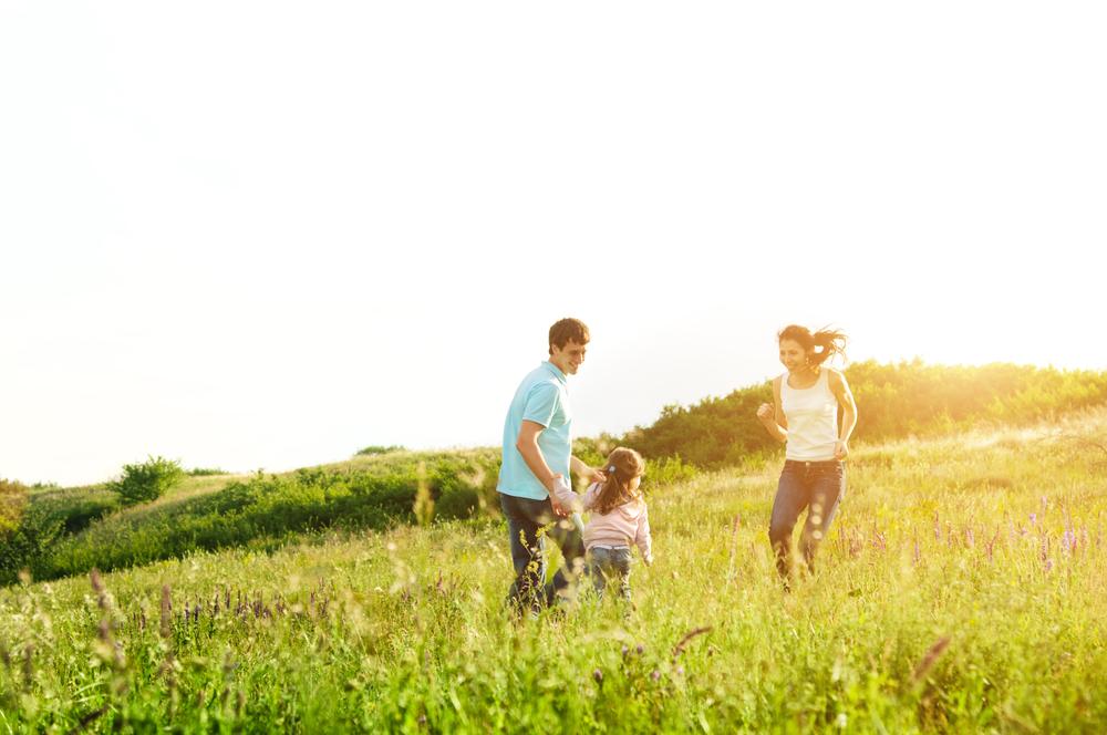 Family reunited and smiling together in a sunny green meadow, enjoying a hopeful moment outdoors.
