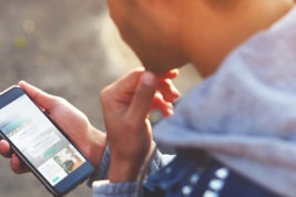 Person holding a smartphone outdoors, researching addiction treatment options on the screen.